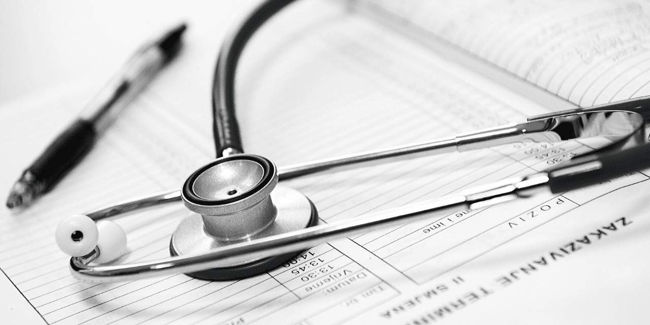 A stethoscope rests on a sheet of paper alongside a pen, symbolizing medical documentation and care.