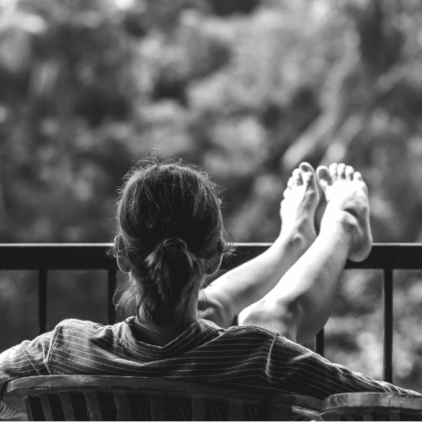 Woman sitting with her feet up on a rail with a fresh coconut water next to her
