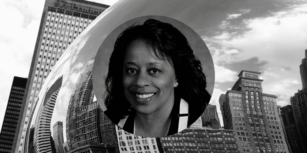 A black and white image of a woman standing in front of a large bean sculpture, showcasing her contemplative expression.