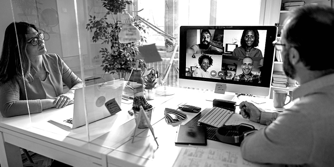 A man and woman seated at a desk, focused on a computer screen in a collaborative work environment.