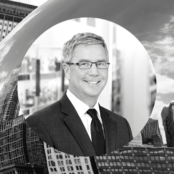 A man in glasses and a suit stands confidently in front of a large bean sculpture, showcasing a unique artistic display.