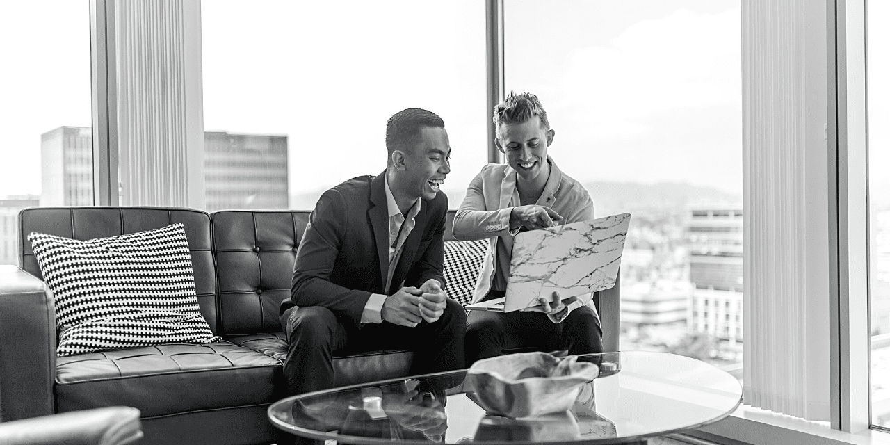 Two men seated on a couch, intently examining a map together, planning their next adventure.