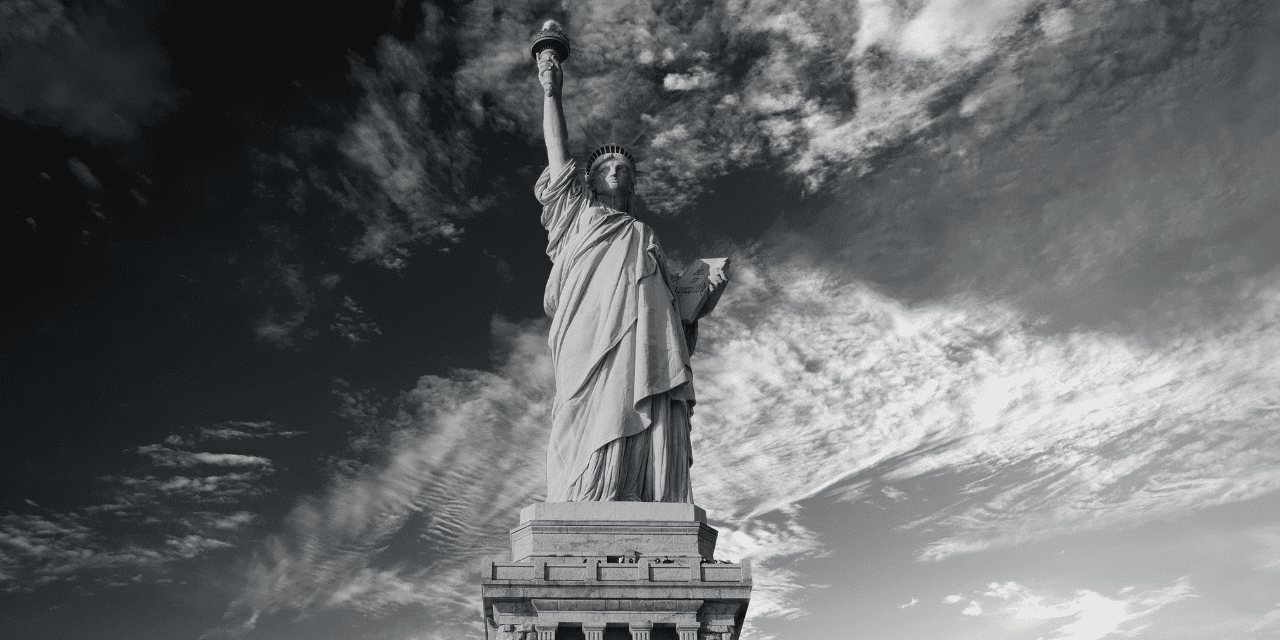 The Statue of Liberty stands tall in New York City, symbolizing freedom and democracy against a clear blue sky.