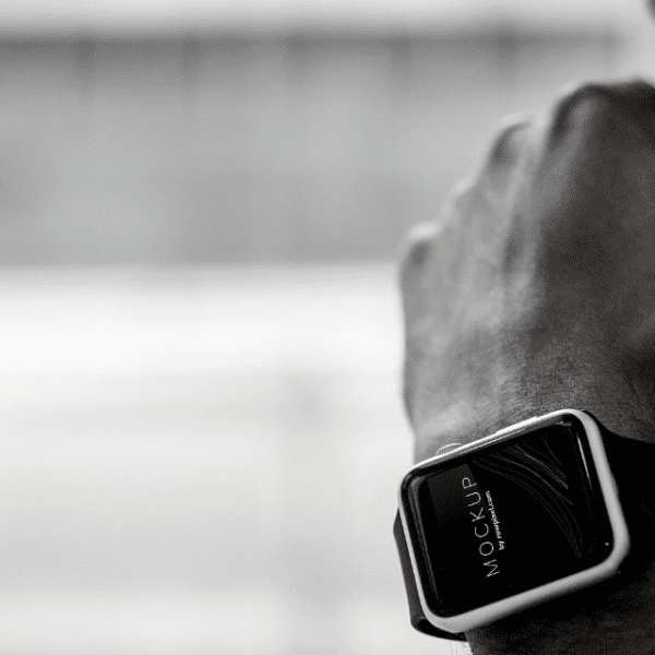 Black and white image focusing on a smartwatch worn by a person in thought, background blurred.