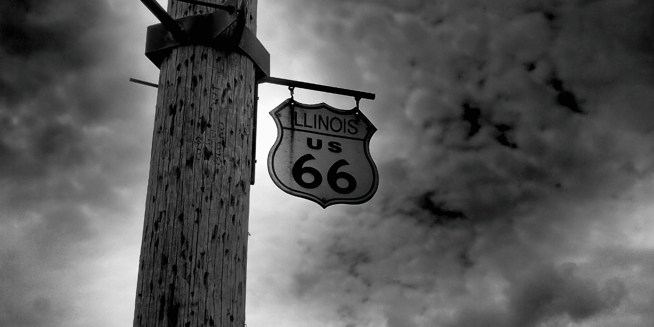 A black and white image of a Route 66 sign, showcasing its iconic design and vintage appeal.