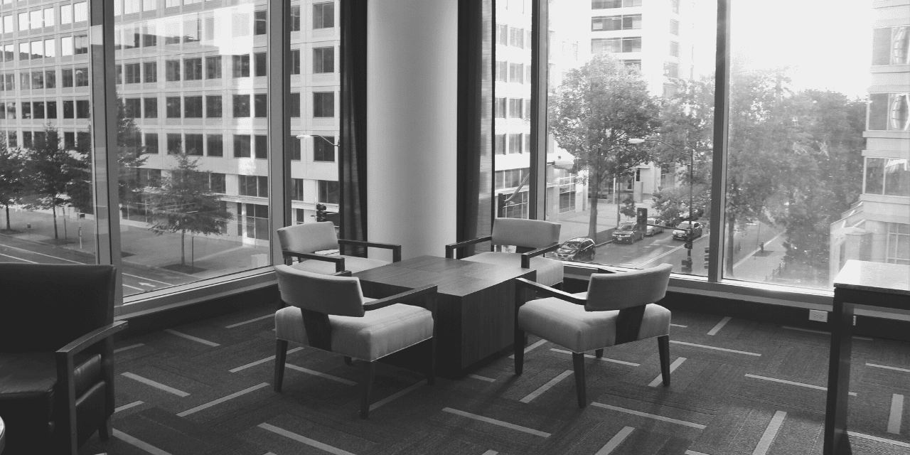 A black and white image depicting a room furnished with chairs and a table, showcasing a minimalist interior design.
